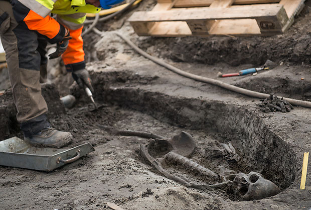 Bild på arkeolog som gräven en grav i Nya Lödöse