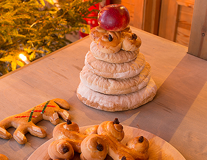 Julhög med fyra brödkakor, överst i högen lussekatt och äpple.
