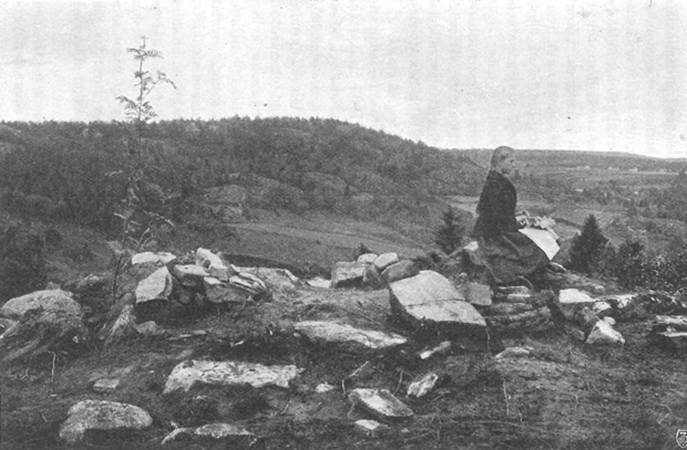 Kopia på svartvitt foto med ung kvinna som sitter på stenar.